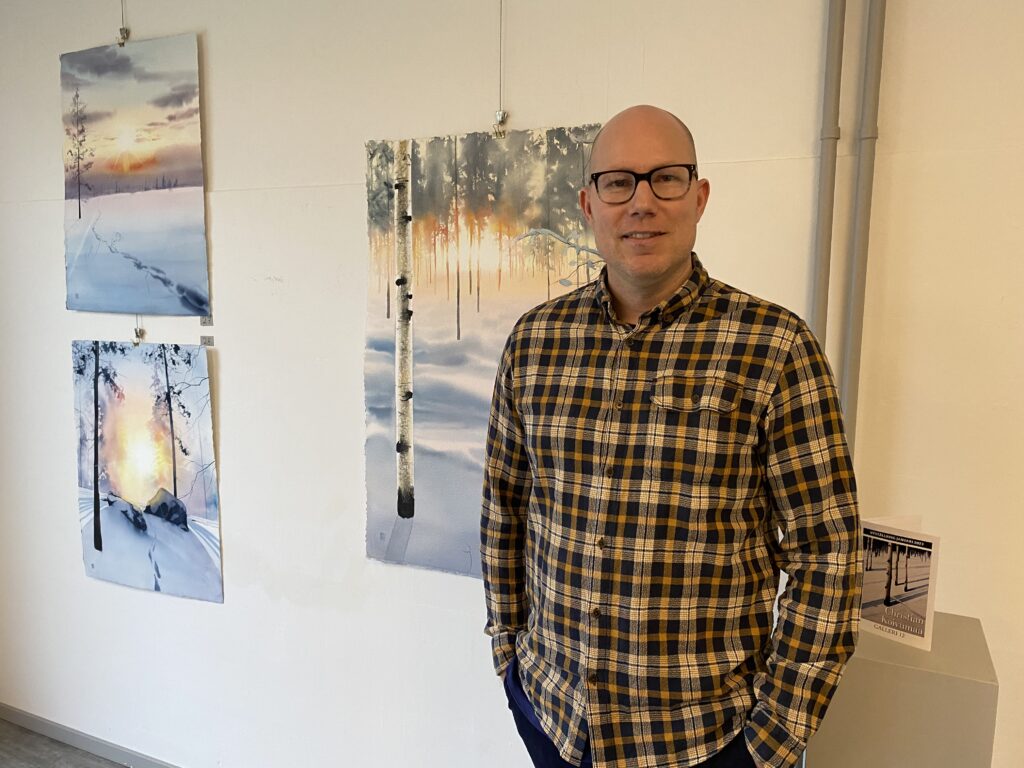 Foto som föreställer konstnären Christian Koivumaa framför sina målningar